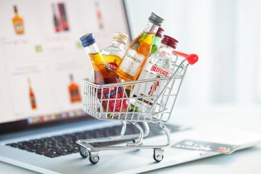 Minsk, Beyaz Rusya - 16 Ocak 2018: Mini alışveriş sepeti dolu küçük alkol şişeleri - Camus ve Martell konyak, Havana club ROM, Beefeater cin dizüstü bilgisayar arka plan açıklayıcı editoryal fotoğrafı.