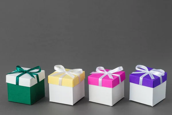 Vier Geschenkboxen mit Bändern auf grauem Hintergrund. Kopierraum für Text. — Stockfoto