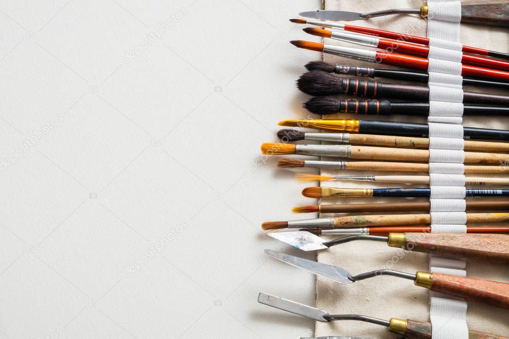 Paintbrushes and palette knifes in textile carry bag. A storage case filled of tools for professional artist work. Copy space for text.