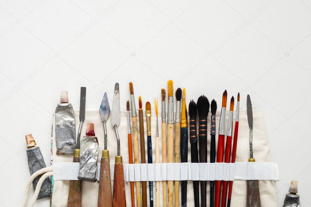Paintbrushes, palette knifes and paint tubes in textile carry bag. A storage case filled of tools for professional artist work. Copy space for text.
