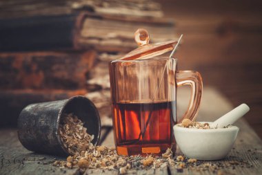 Tentür veya cam, havan sağlıklı daisy otlar ve eski kitaplar sağlıklı çay.