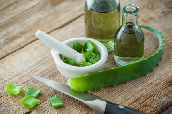 Foglia di aloe vera, malta bianca piena di aloe tritata e bottiglie di gel di aloe o infuso . — Foto Stock