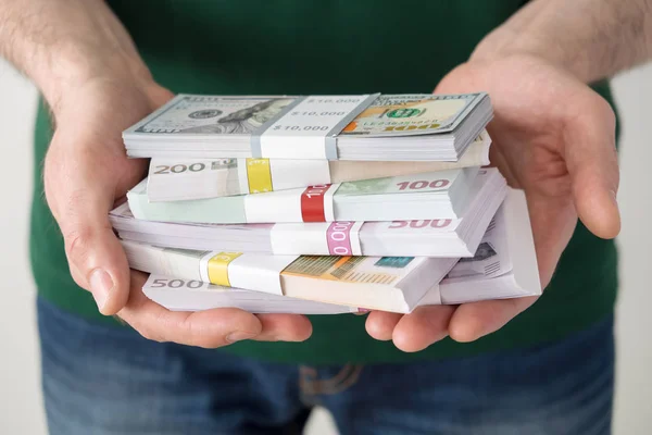 Man die een heleboel euro's en dollars in zijn handen. — Stockfoto