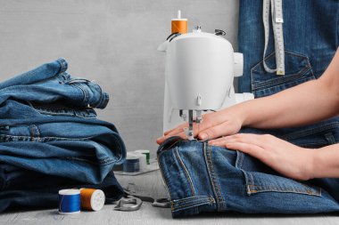 Sewing denim jeans on sewing machine in tailor workshop. Jeans repair.  clipart
