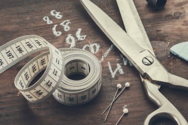 Terzi makası, mezura, iğne, tebeşir dahil yüksük. İnsan bedeni ölçümleri tahtanın üzerine yazılır..