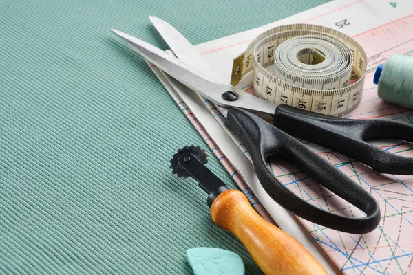 Skräddarsydda artiklar: sax, måttband, trådrullar på papper, sömmerskniv, krita på grön trikå. — Stockfoto