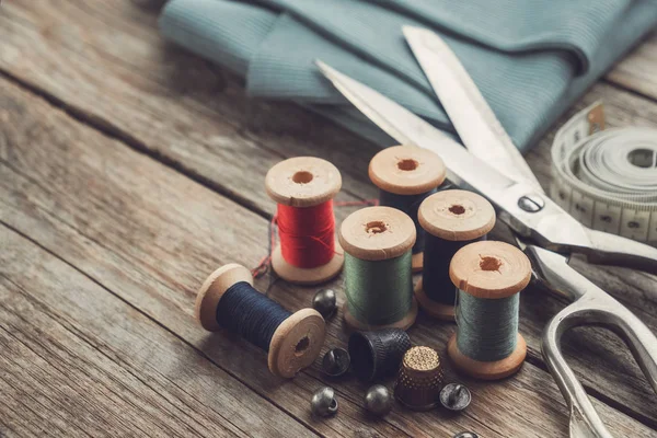 复古缝纫用品：裁剪、顶针、纽扣、木制线轴、测量带和绿色面料. — 图库照片