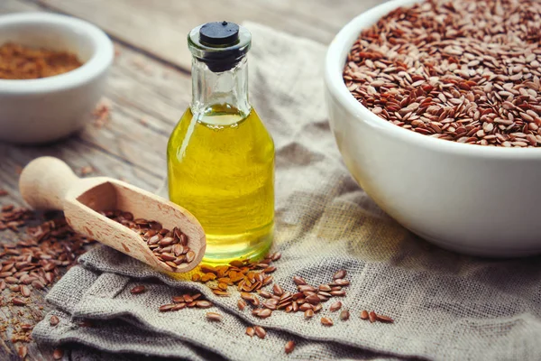 Mortar of flax seeds and bottle of fresh linseed oil on linen cloth. — Stock Photo, Image