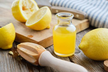 Limon suyu ya da yağ şişesi, ahşap sıkacağı ve limonlu narenciye.