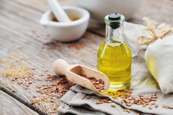 Botella de aceite de linaza fresca, cucharada de madera de semillas de lino en tela de lino. Mortero sobre fondo . — Foto de Stock