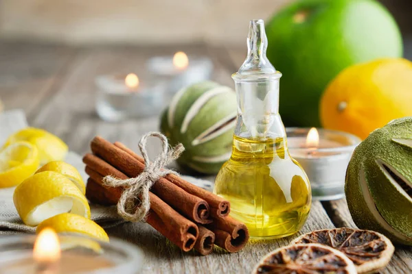 Botella de aceite esencial de limón cítrico para aromaterapia, cítricos, palitos de canela y velas . — Foto de Stock