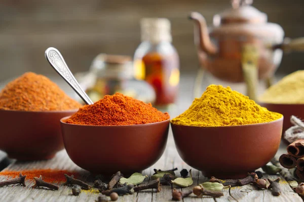 Aromatiska kryddor och örter: röd chilipeppar, gurkmeja, curcuma, kardemumma, kanel, kryddnejlika, anis, paprika, oljeflaskor och tekanna. Ingredienser för matlagning och Ayurveda behandlingar. — Stockfoto