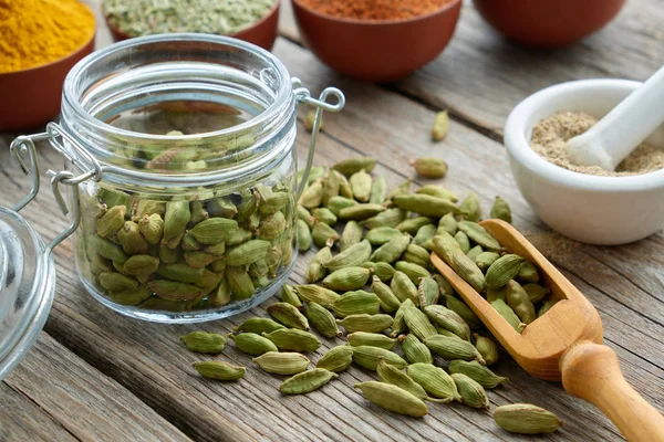 Green cardamom pods. Jar of whole cardamom pods and mortar of crushed seeds. — 스톡 사진