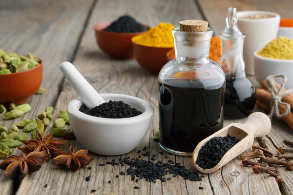 Σπόροι μαύρου κύμινου ή ρωμαϊκού κόλιανδρου, μπουκάλια μαύρου ελαίου κύμινου. Υλικά για μαγείρεμα. Θεραπείες Ayurveda. — Φωτογραφία Αρχείου