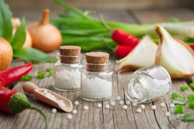Soğan soğanı, yeşil soğan, kırmızı biber ve bir şişe homeopatik globula. Homeopatik ilaçlar..