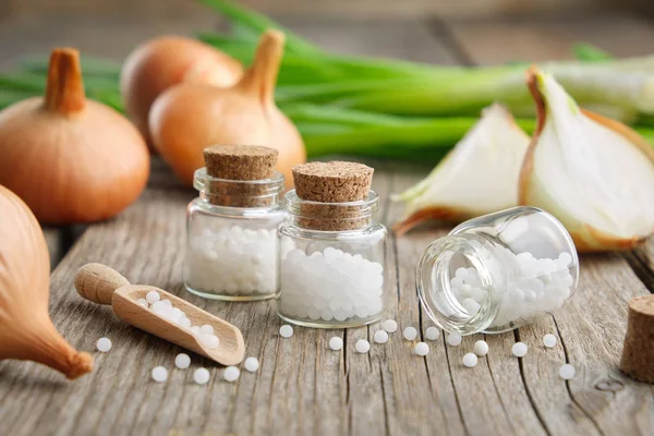 Uienbollen, groene uien en flessen homeopathische bollen. Allium cepa homeopathische geneesmiddelen. — Stockfoto