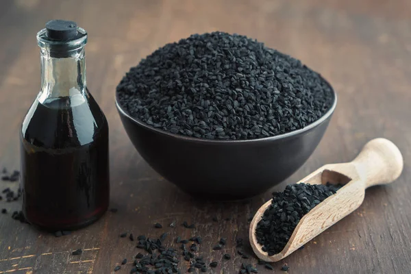 Cominho preto ou sementes de coentro romano e garrafa de óleo de cominho preto. Ingredientes para cozinhar. Tratamentos Ayurveda . — Fotografia de Stock