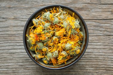 Sağlıklı takvim çiçekleri. Tahta tahtada bir kase kuru kadife yaprağı. Üst Manzara. Bitkisel ilaçlar.