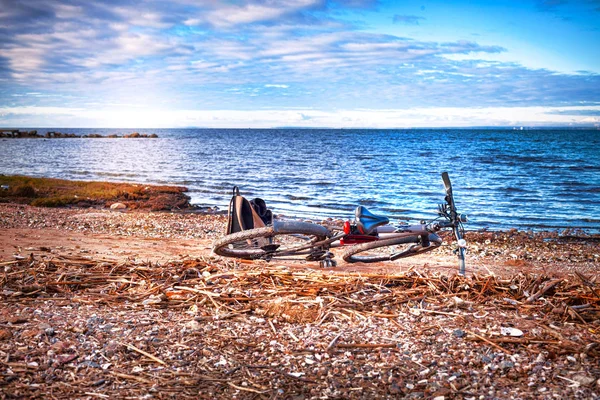 Велосипед и рюкзак лежат на диком берегу моря — стоковое фото