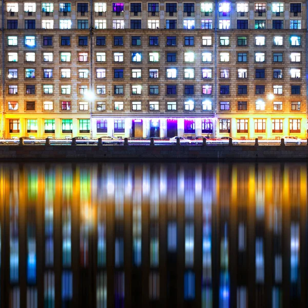 Una vista nocturna de las ventanas de una casa multifamiliar con reflejos Fotos de stock libres de derechos