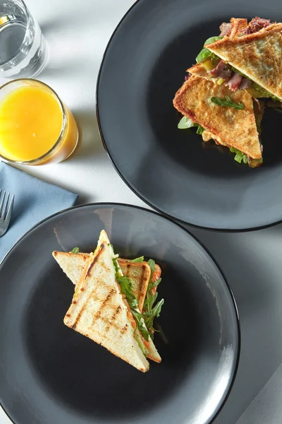 Бутерброды на тарелках и свежий сок — стоковое фото
