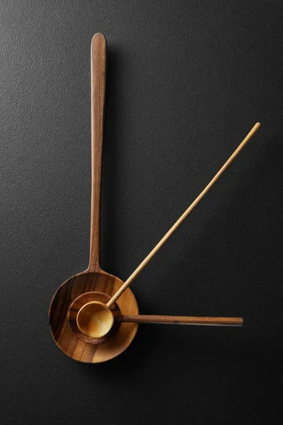 Vista superior del reloj despertador negro con cucharas de madera —  Fotos de Stock
