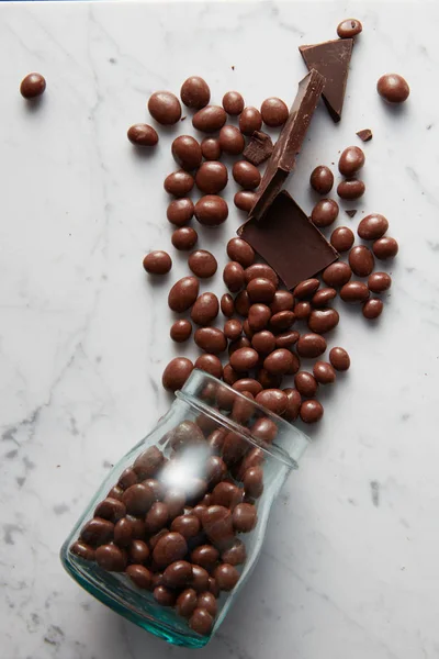 Bolas de chocolate dispersas del frasco de vidrio — Foto de Stock
