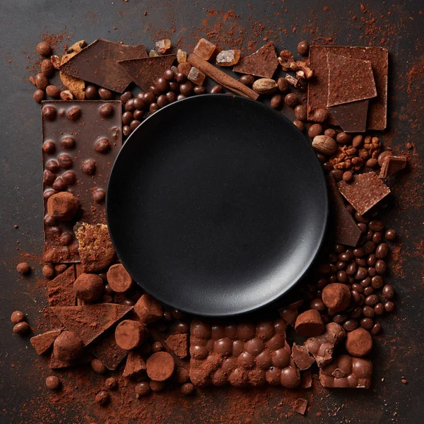 Рамка из различных шоколадных конфет с черной пластиной — стоковое фото