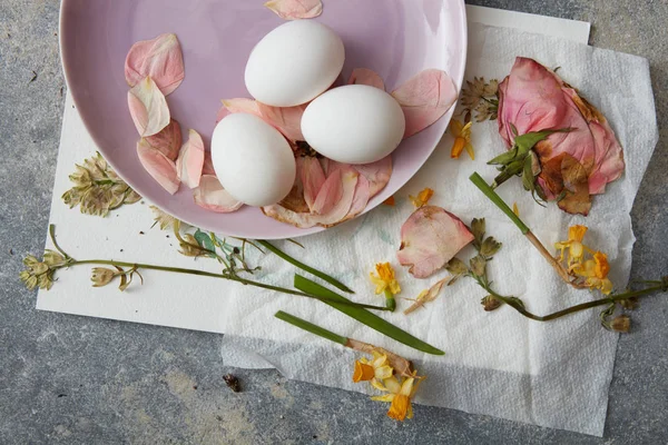 Ovos em prato com pétalas de flores — Fotografia de Stock