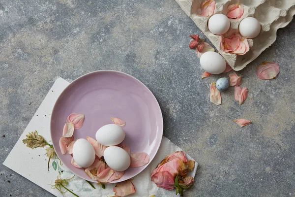 Яйця на тарілці з пелюстками квітів — стокове фото