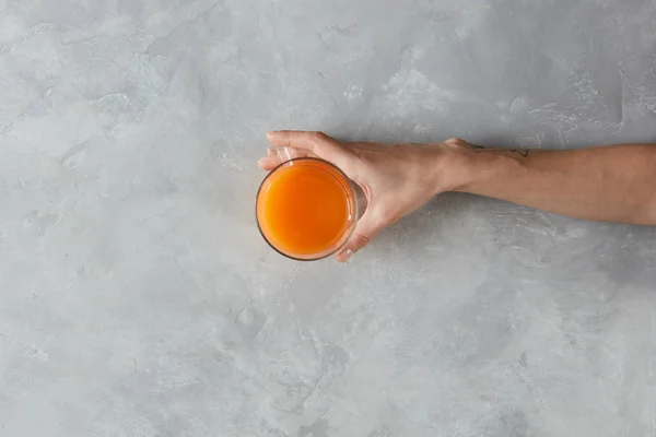 Χέρι που κρατά ποτήρι χυμό πορτοκαλιού — Φωτογραφία Αρχείου