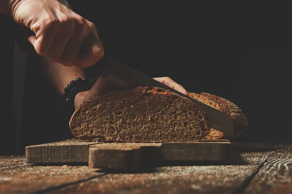 Человек нарезает свежий хлеб — стоковое фото