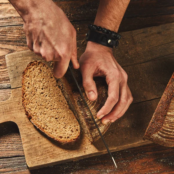 Man slicing fresh loaf of bread — Stock Photo, Image