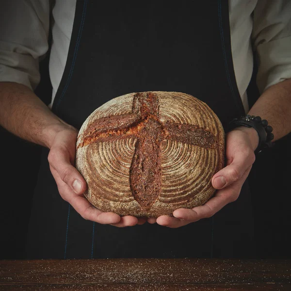 Las manos del panadero sostienen un pan fresco —  Fotos de Stock