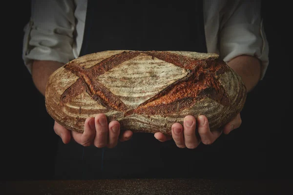 Las manos del panadero sostienen un pan fresco — Foto de Stock