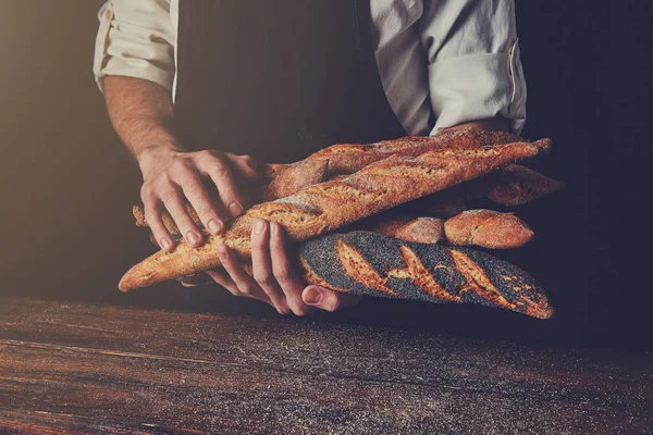 Hombre sosteniendo baguettes recién horneados — Foto de Stock