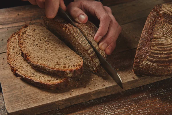 Руки режут ржаной хлеб — стоковое фото