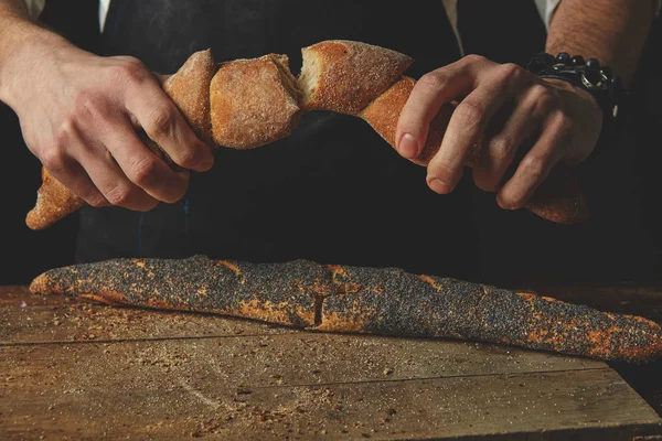 Mannelijke handen remmen stokbrood — Stockfoto