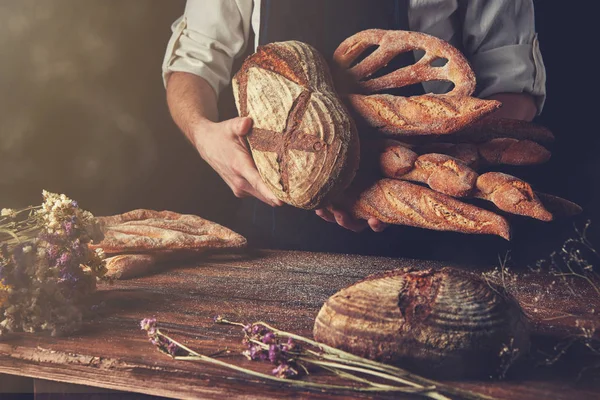 Пекарь хранит разнообразный деревенский хлеб — стоковое фото