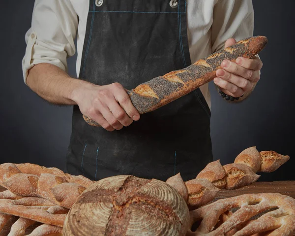 Пекарь хранит разнообразный деревенский хлеб — стоковое фото