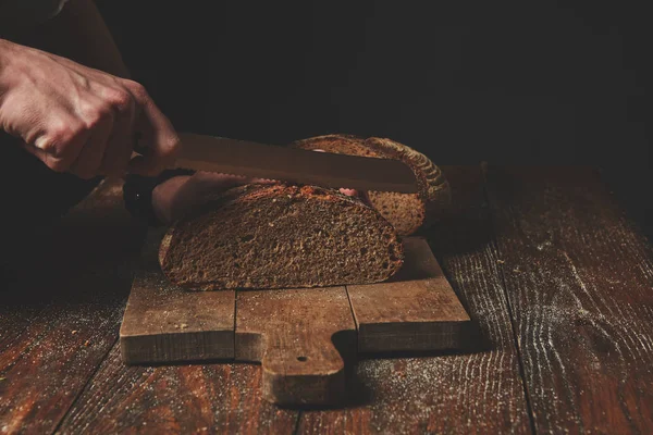 Hombre cortar pan de grano de centeno — Foto de Stock