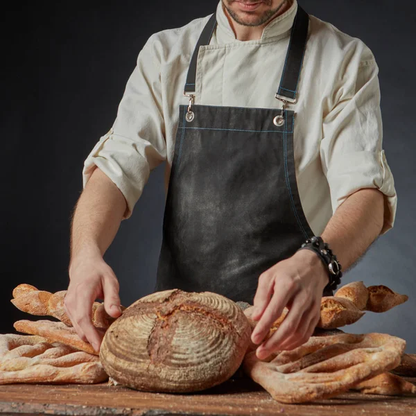Чоловічий пекар з різноманіттям свіжого хліба — стокове фото