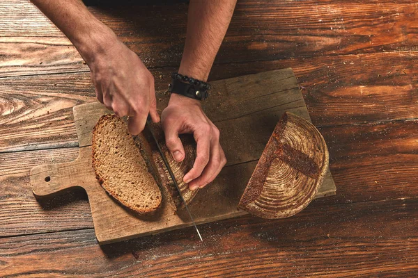 Человек режет свежеиспеченный хлеб — стоковое фото