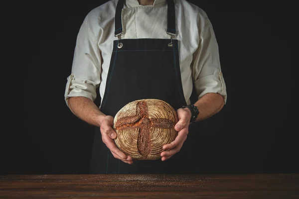 Bakker in schort houden van zelfgebakken brood — Stockfoto