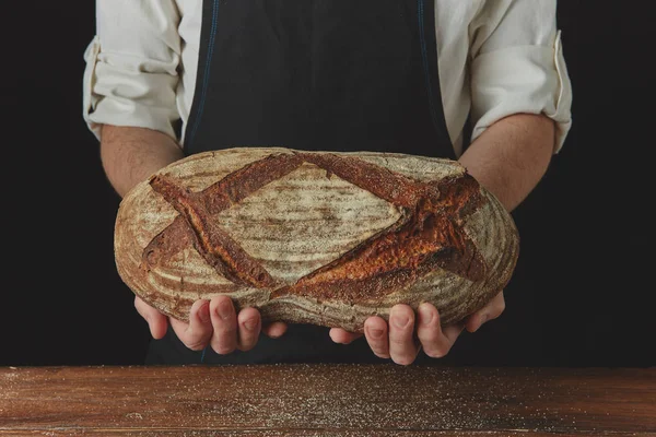 Baker v zástěře drží domácí chléb — Stock fotografie