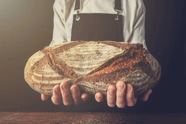 Baker holding fresh oval bread — Stock Photo, Image