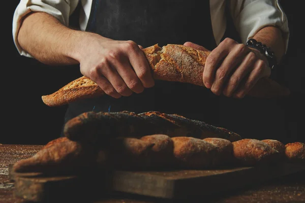 Baker lámání křupavou bagetou — Stock fotografie