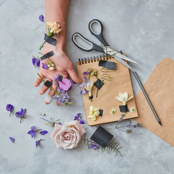 Mão masculina com caderno e flores — Fotografia de Stock