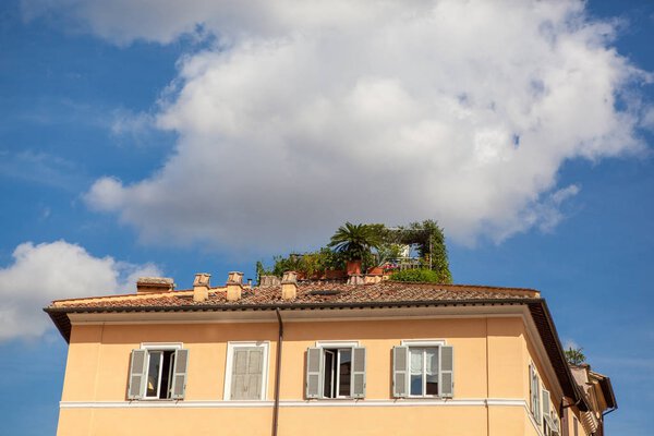 Closeup of roof of ancient building with blue sky and white clouds in Rome City, Italy