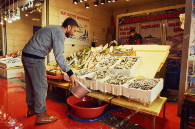 Istanbul, Turkey - November 25,2017: Fish market in Istanbul. The man pouring water at the fish clipart